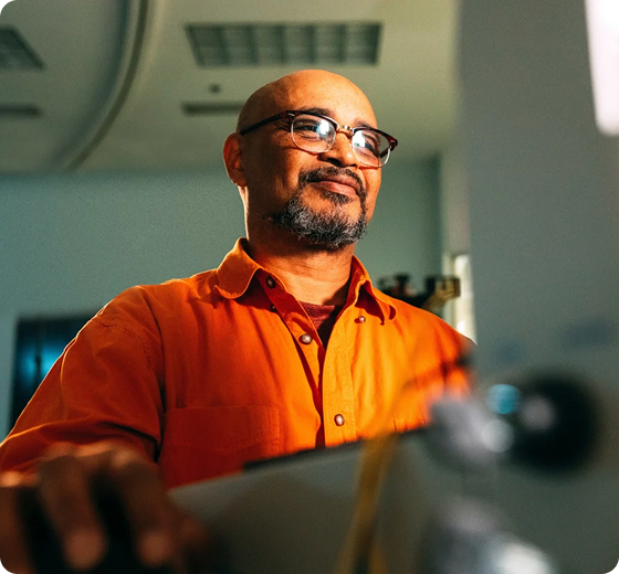 person with orange shirt standing in front of computer