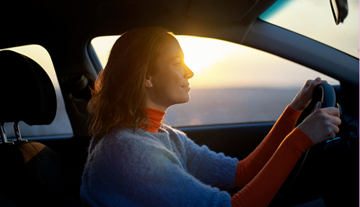 person driving a car while the sun is setting