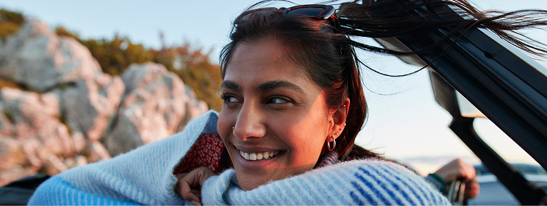 person leaning on car with hands folded under chin